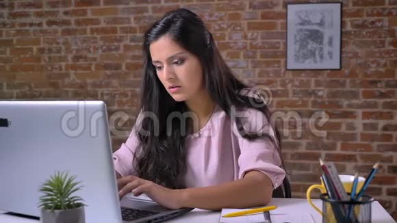 聪明的白种人漂亮的女孩在她的笔记本电脑上打字然后犯错误显示出失败的标志遮住她的头视频的预览图