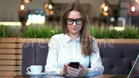 时尚女性戴眼镜和白衬衫的肖像使用智能手机输入信息视频的预览图