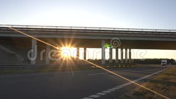阳光明媚的日落背景下的高速公路上有一座桥上面有食品货车后车厢视频的预览图