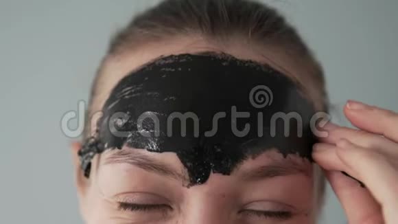 一个女人从她的额头上取出一个黑色胶卷面具的残骸视频的预览图