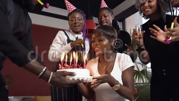 英俊迷人的非洲女孩在生日蛋糕上吹蜡烛包围了她的朋友视频的预览图