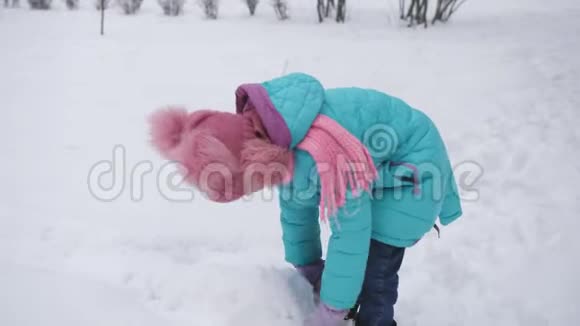 一个小女孩滚动一团雪来创造一个雪人视频的预览图