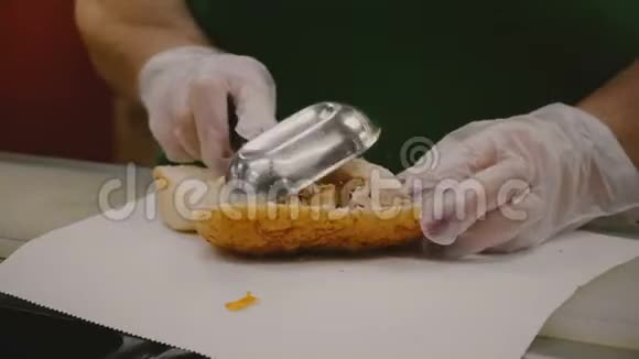 制作一个大鸡肉三明治的过程中人类的手用工具把配料放在大面包片上视频的预览图