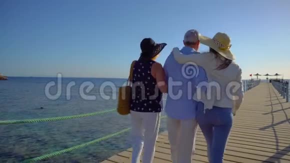 年长夫妇和他们的成年女儿在红海码头散步一家人享受假期视频的预览图