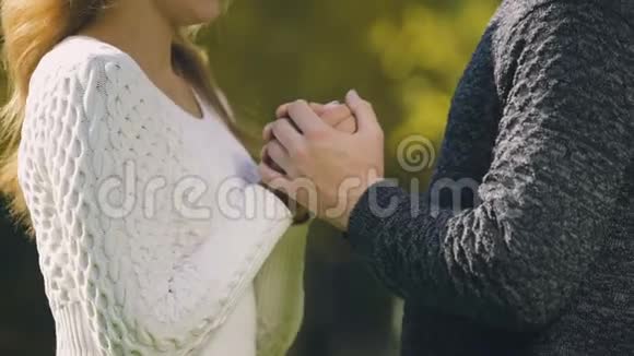 冻僵的情侣穿着毛衣在秋天的公园里温暖双手互相拥抱互相关心视频的预览图