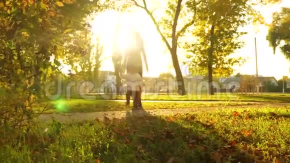 日落时分母亲和孩子一起在秋天公园散步孩子正在美丽的阳光下沿着小路走视频的预览图