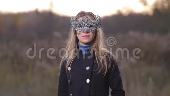 一个金发女孩站在地平线上戴着一个漂亮的面具戴上面具露出可爱的笑容视频的预览图