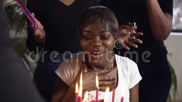 英俊的非洲女孩在生日蛋糕上和她的朋友在背景上吹蜡烛视频的预览图