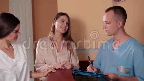 护士和医生穿着蓝色医用长袍站在接待处咨询视频的预览图