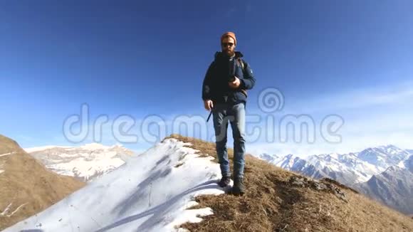 快乐的旅行者留着胡子的人带着相机和背包带着太阳镜在雪地的背景下上山视频的预览图