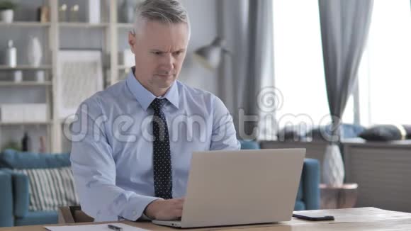 灰色头发商人与脊柱背部疼痛坐在工作视频的预览图