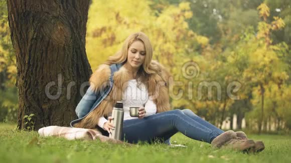 女人倒热茶暖饮料秋林野餐视频的预览图