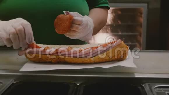 用火腿和意大利腊肠做一个特大号肉三明治的过程人的手把配料放在大面包上视频的预览图