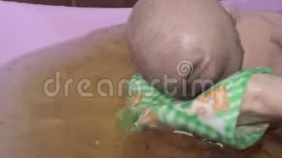 父母的手在洗澡时给新生婴儿洗澡视频的预览图