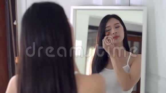 美女肖像亚洲女人用刷子涂妆在室内照镜子视频的预览图