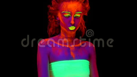 一个美丽的半裸少女交叉双手在黑光中用发光的颜料在身上跳舞视频的预览图