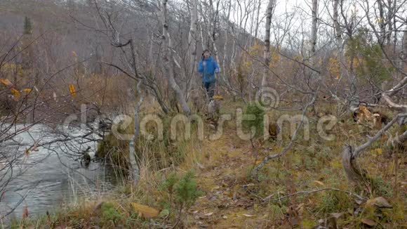 一个人带着背包在一个美丽的公园里旅行他沿着一条山河的河岸散步美丽的秋天视频的预览图