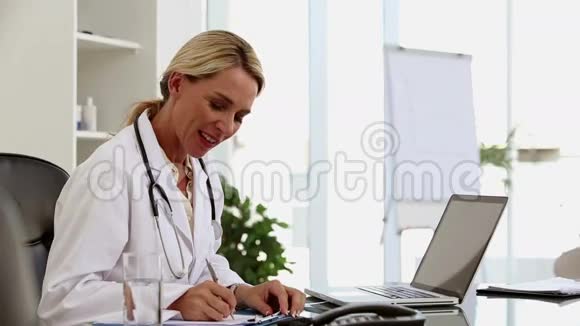 忙碌的医生在她的办公桌前工作视频的预览图