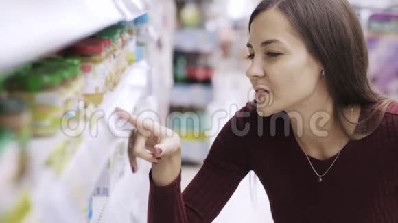 女人的肖像是在超市里寻找价格标签和产品视频的预览图