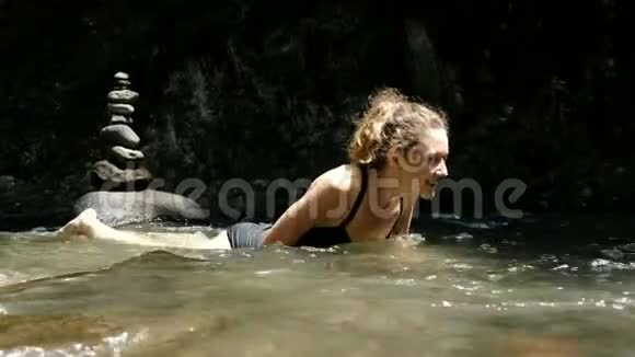 穿着泳衣的年轻女子躺在一条冰冷的河流里在冰冷的河水中发出情感上的尖叫视频的预览图