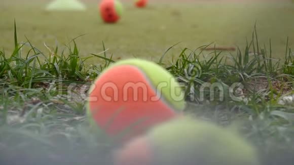 五颜六色的网球躺在网球场上的草地上背景缓慢视频的预览图