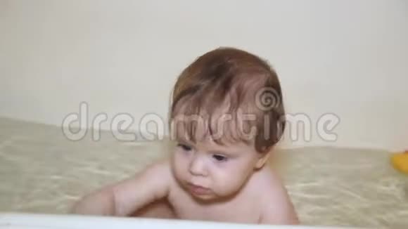 小幸福宝宝正在洗澡间里玩鸭子笑眯眯的妈妈在浴室给婴儿洗澡水上游戏视频的预览图