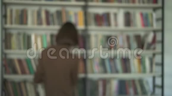 图书馆书架背景上模糊的男学生照片视频的预览图