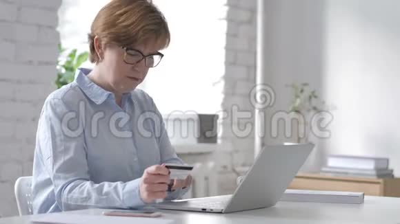 由老妇人在笔记本电脑上使用信用卡在线购物视频的预览图