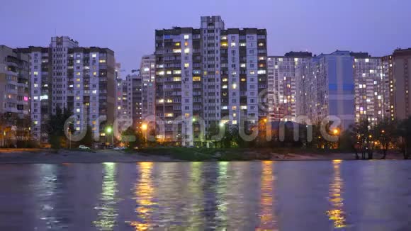 傍晚城市的公寓大楼在大湖附近路灯在水中反射视频的预览图