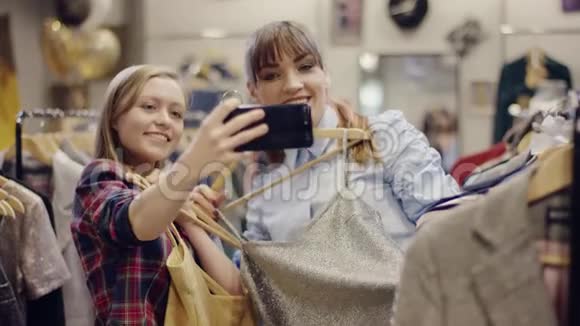 年轻漂亮的女人在服装店里试穿衣服时和女朋友合影视频的预览图