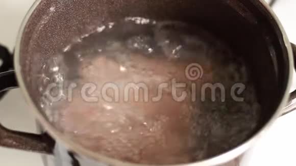 肉食香肠是用平底锅煮的沸腾的水蒸气用金属勺子搅拌午餐烹饪视频的预览图
