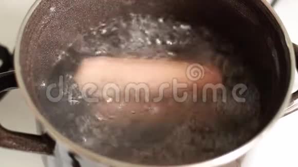 肉食香肠是用平底锅煮的沸腾的水蒸气用金属勺子搅拌午餐烹饪视频的预览图