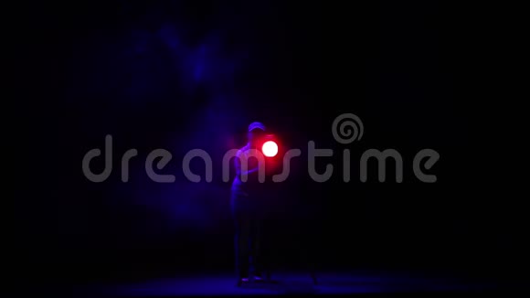 一个女照明师用一阵烟把一束光从聚光灯射进大厅视频的预览图