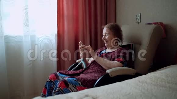 老妇人写了一条信息看着她智能手机上的照片奶奶的皱纹很深印支快乐的学长视频的预览图