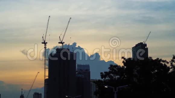 在美妙的夕阳下起重机和建造摩天大楼的剪影在大城市的建筑视频的预览图