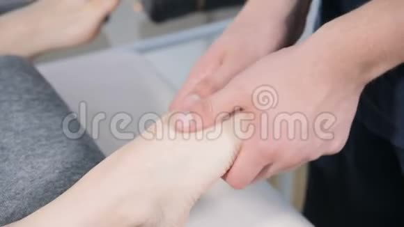 一名男性理疗师在美容和健康水疗中心为一名成年妇女做足底按摩足部和身体护理视频的预览图