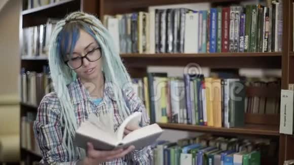 戴眼镜的年轻时髦女子戴着可怕的眼镜在图书馆的镜头前看书的画像视频的预览图