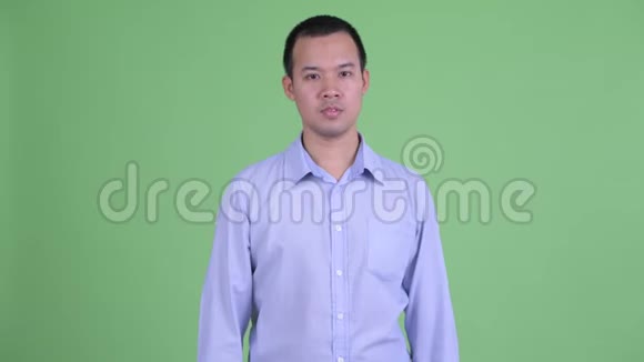 困惑的亚洲商人在竖起大拇指和竖起大拇指之间做出选择视频的预览图