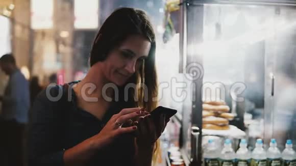 快乐迷人的女性首席执行官使用智能手机电子商务应用程序附近蒸街食品供应商在晚上纽约市视频的预览图