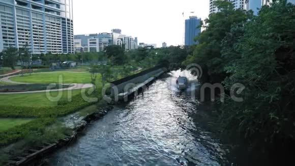 船浮在摩天大楼旁边的城市运河上城市景观混凝土建筑绿树和水视频的预览图