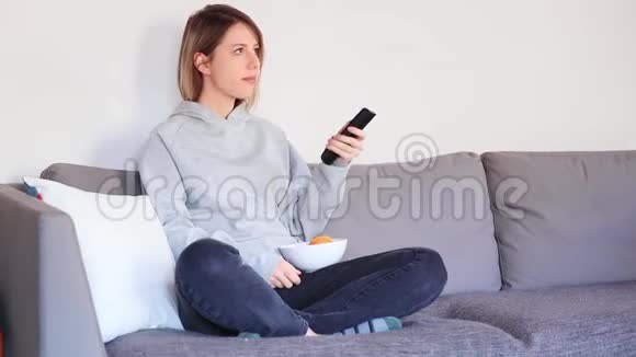 年轻女子拿着遥控器看电视视频的预览图