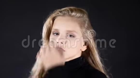 黑色背景画室小模型的肖像抚摸她的头发看着相机摆姿势4k视频的预览图