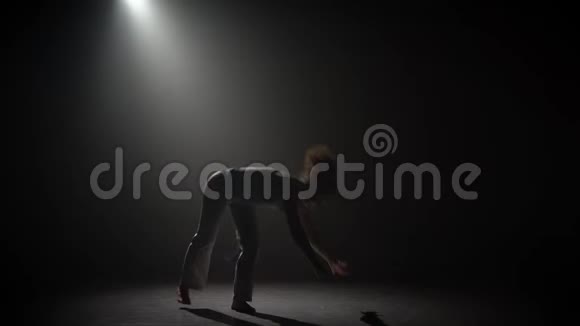 卷曲的女性在黑暗中练习卡波伊拉对抗演播室的聚光灯视频的预览图