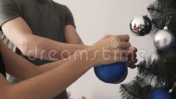 一对夫妇用漂亮的蓝银色球装饰家中的杉树视频的预览图