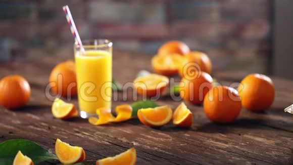把橙子和果汁放在木制背景的玻璃杯里切碎视频的预览图