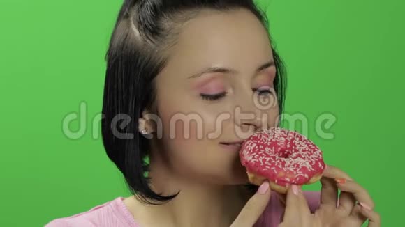 美丽的年轻女子非常高兴地吃甜甜圈铬键视频的预览图