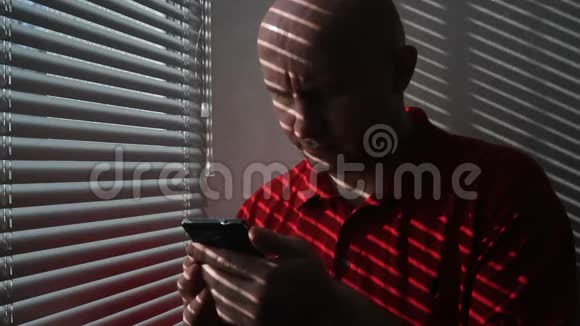 一名身穿红色t恤的男子在办公室里浏览手机信息视频的预览图