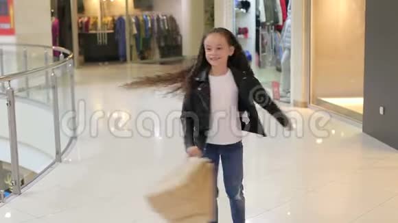 一个小女孩手里拿着包裹在一个时髦的购物中心里纺纱视频的预览图