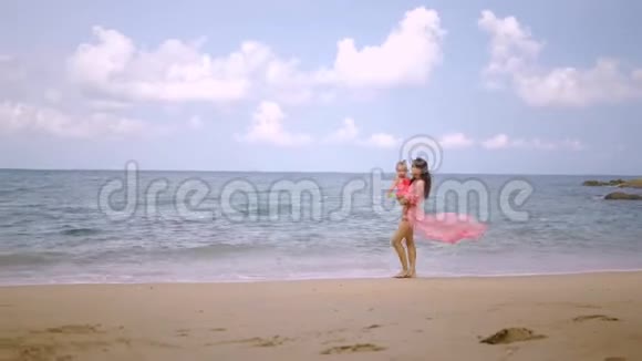 穿着粉红色连衣裙的母女正沿着美丽的海滨散步母亲的概念幸福的童年视频的预览图