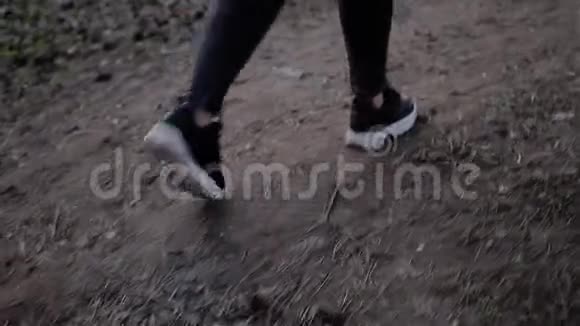 在城市公园的一条土路上穿着黑色牛仔裤和运动鞋的女性腿部特写镜头快关门视频的预览图